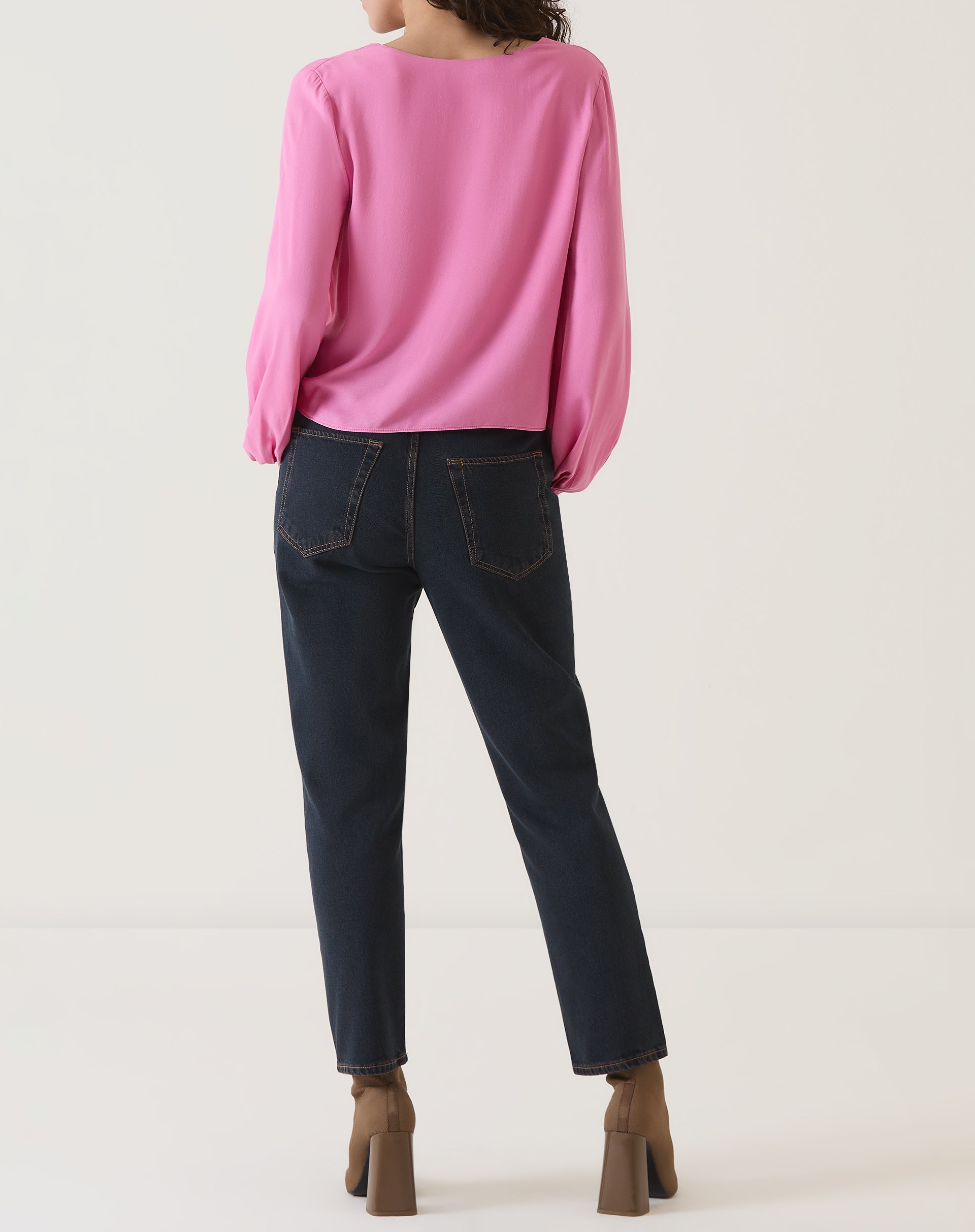 Vista traseira da blusa rosa, mostrando o corte reto e o comprimento até a cintura.