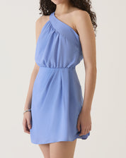 Modelo vestindo um vestido curto assimétrico azul com alça única, vista lateral.