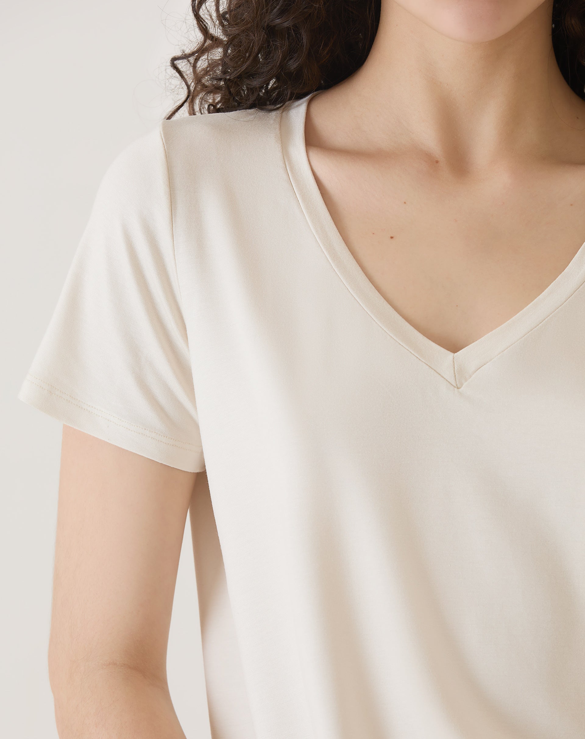 Detalhe do decote em V da camiseta de malha.