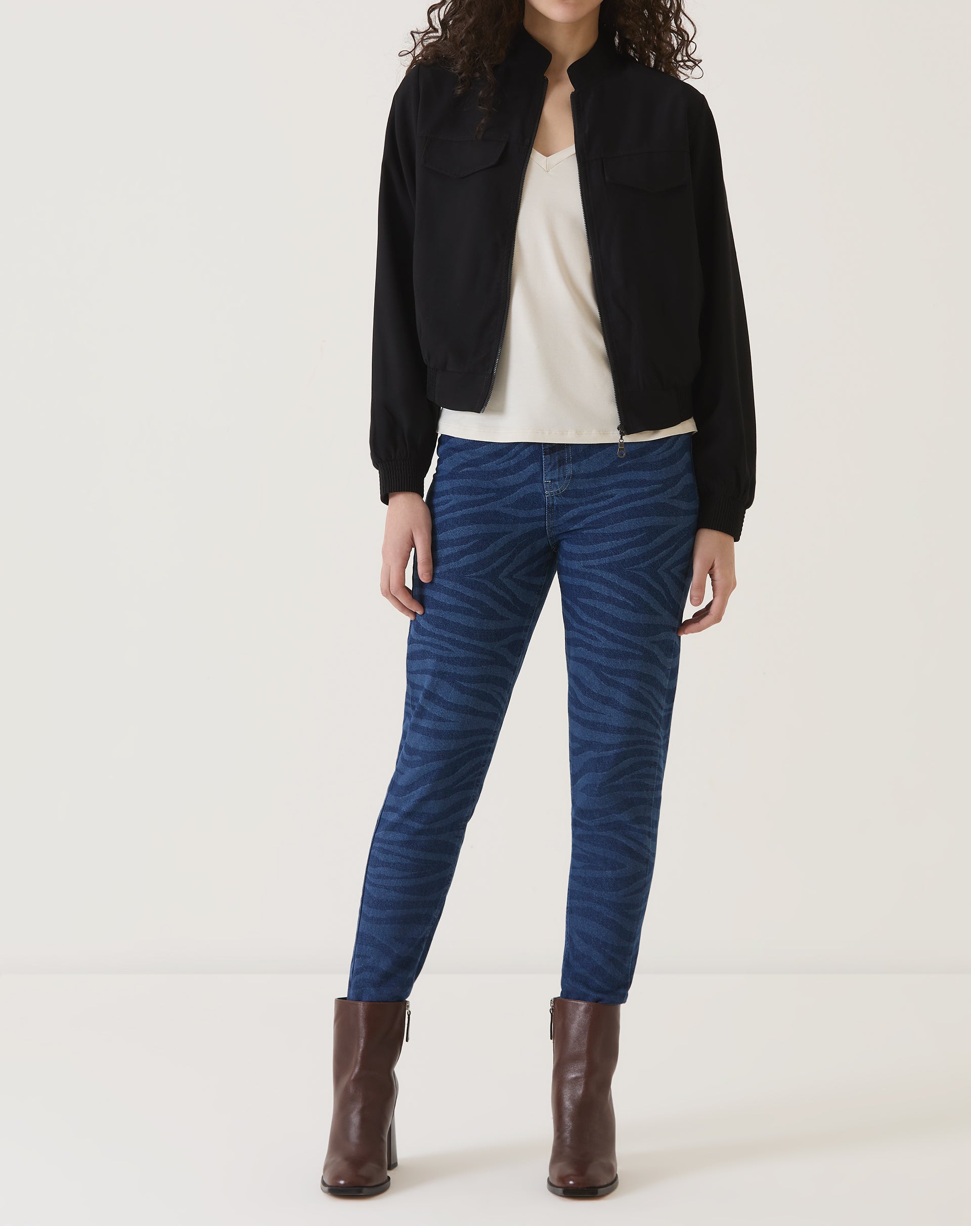 Modelo vestindo a camiseta de malha com jaqueta preta e calça azul.