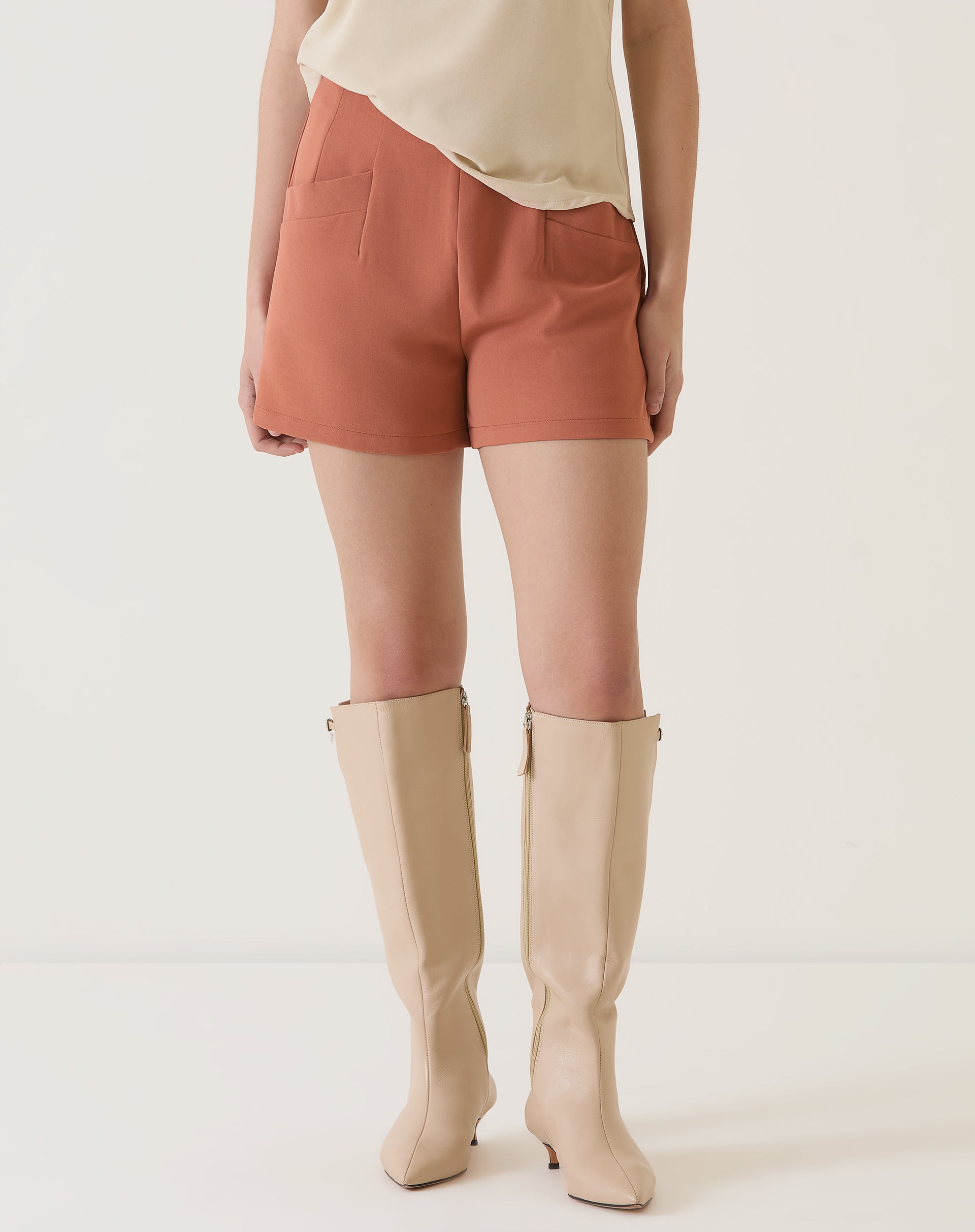 Vista frontal do shorts de alfaiataria vinho com detalhes de pences.