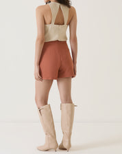 Vista traseira do shorts de alfaiataria vinho com blusa bege.