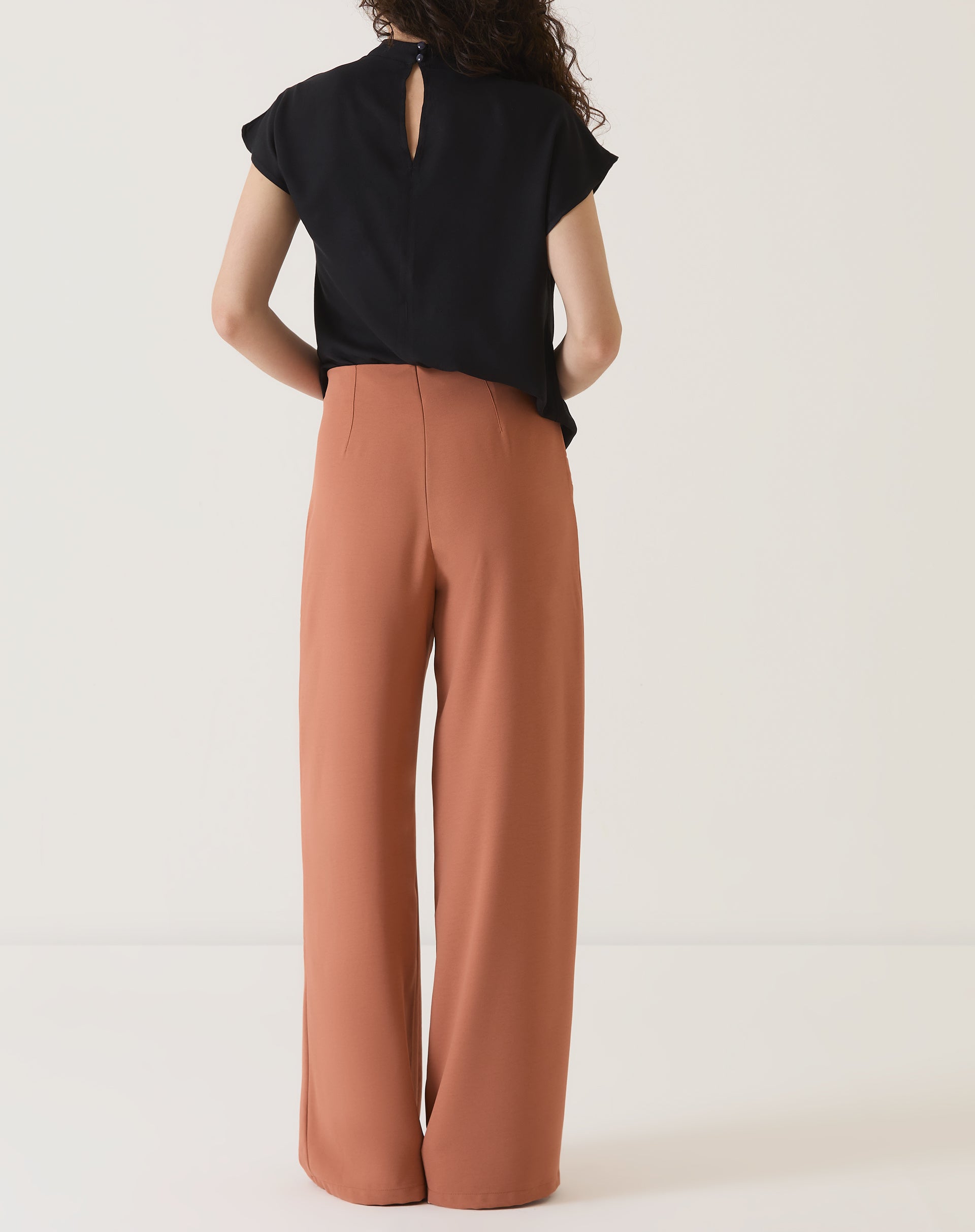 Vista traseira da calça de alfaiataria terracota.