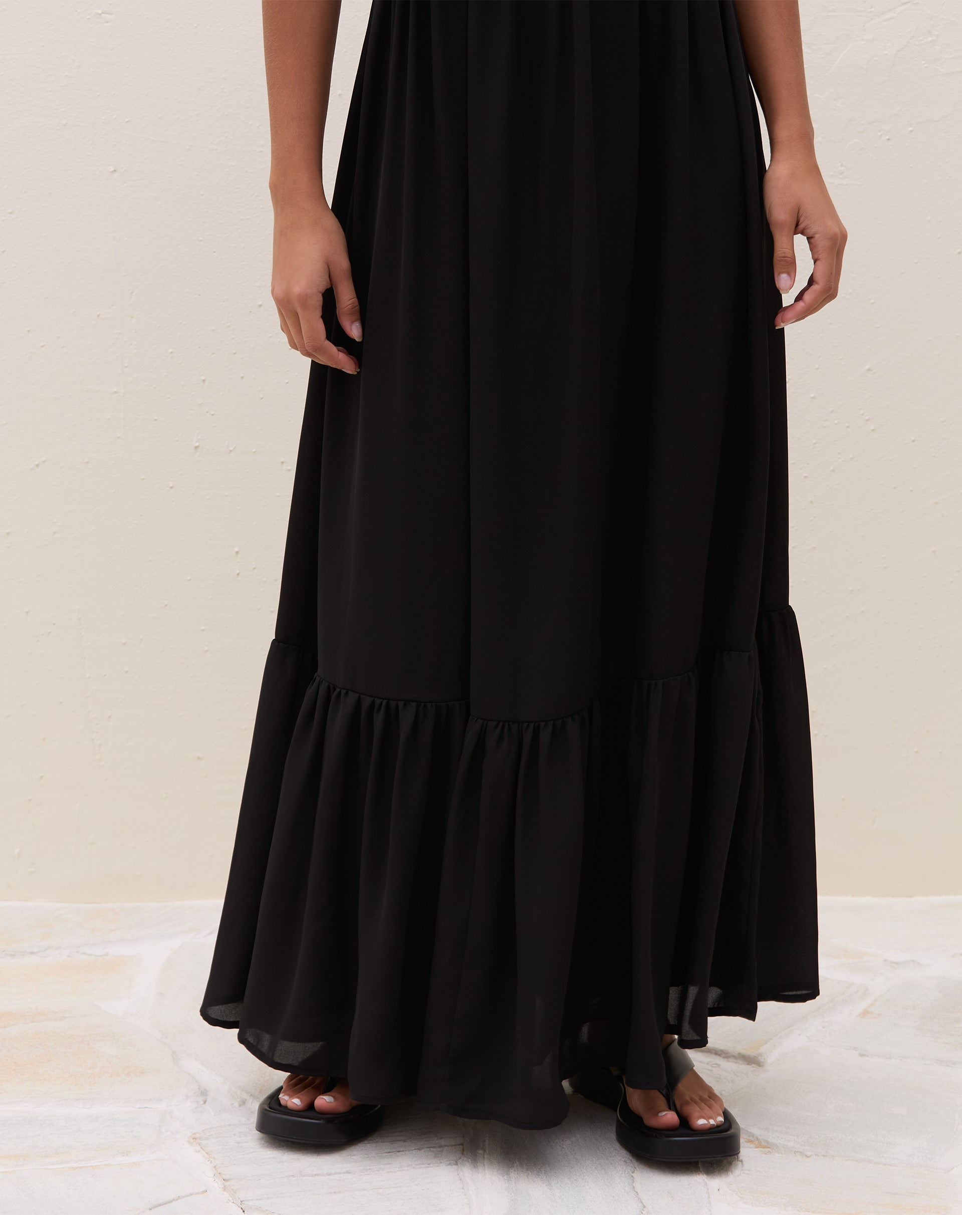 Costas do vestido maxi preto com alças finas ajustáveis, detalhe do recorte superior e encaixe das alças