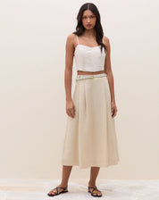 Look completo frontal com top de alcinha estruturado areia, saia midi em tom areia, cinto fino e sandália rasteira