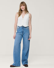 Detalhe do decote em V do colete branco e acabamento da barra arredondada, close do tecido e costura