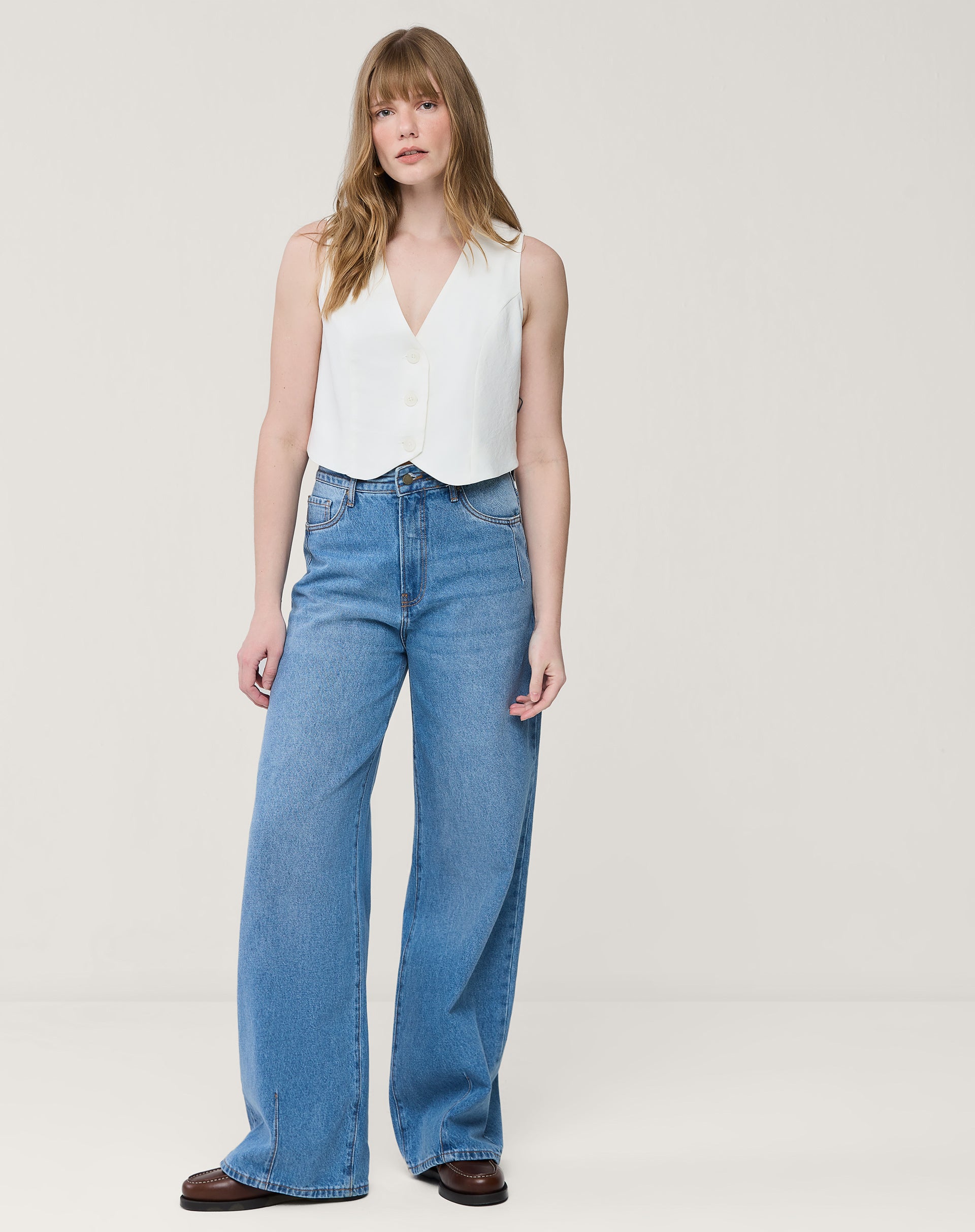 Detalhe do decote em V do colete branco e acabamento da barra arredondada, close do tecido e costura