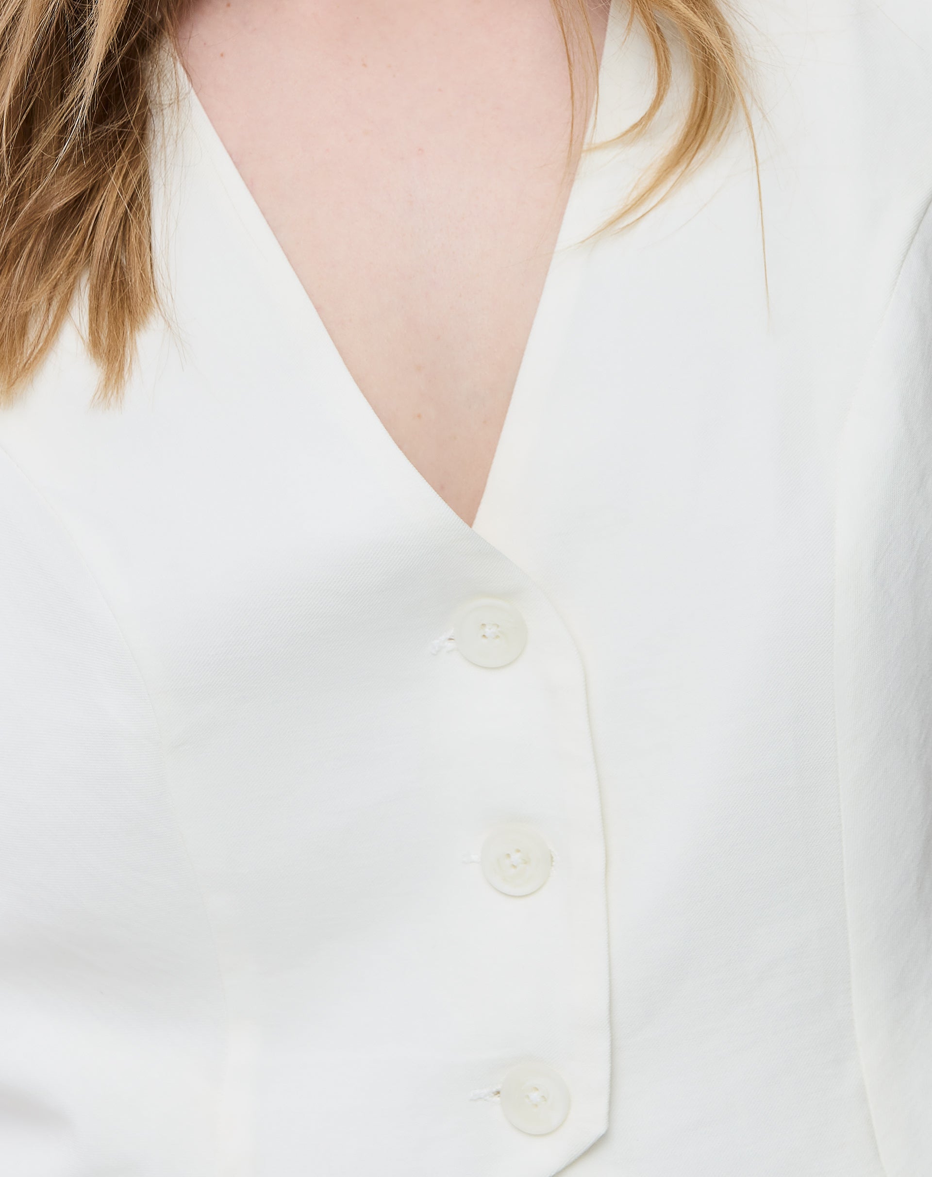 Vista traseira do colete branco cropped mostrando a fenda central na barra e o acabamento limpo