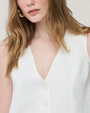 Fechamento com botões frontais em detalhe: botões tom sobre tom e posição central no colete branco