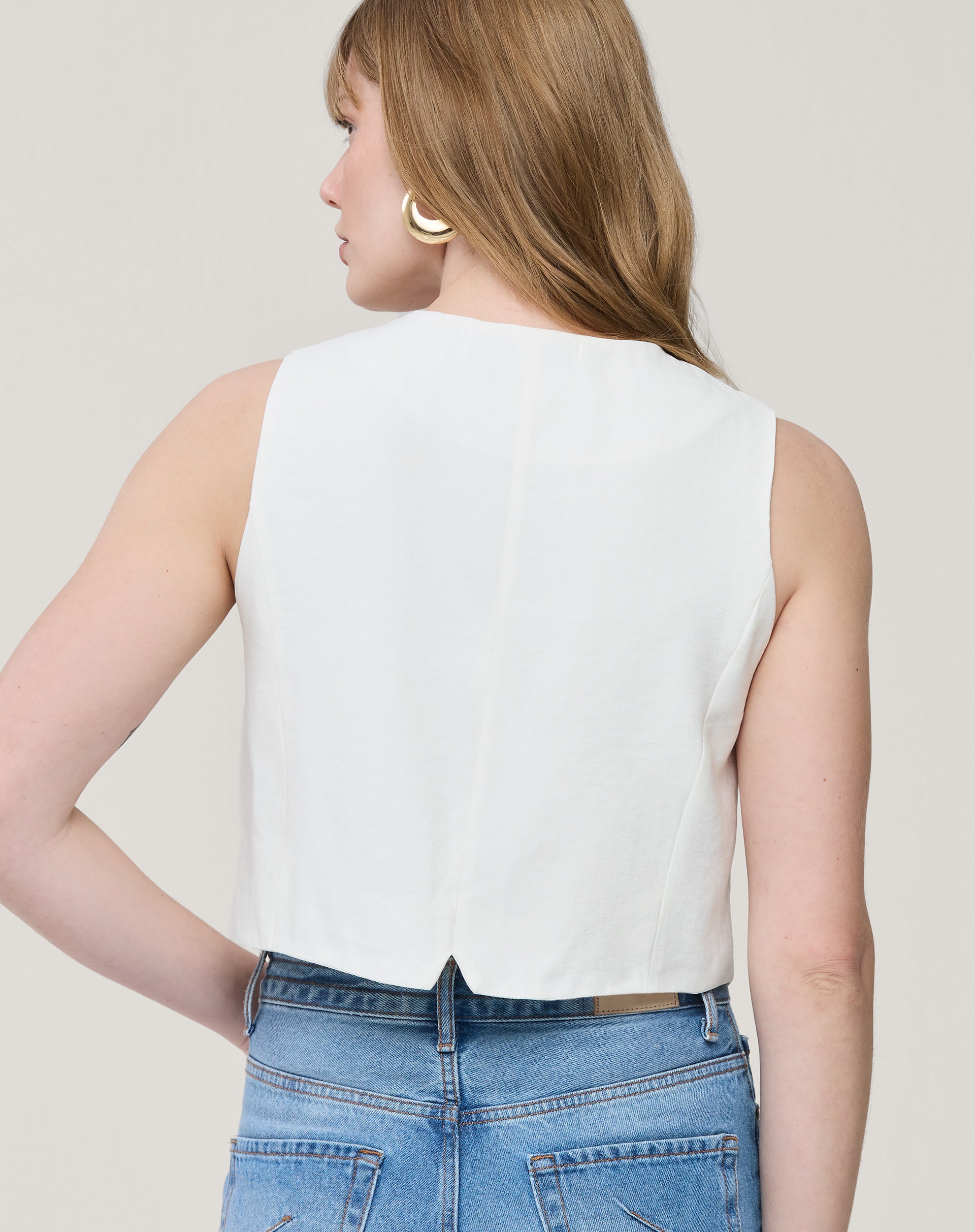 Look completo com colete branco cropped e calça jeans wide leg azul, styling casual contemporâneo