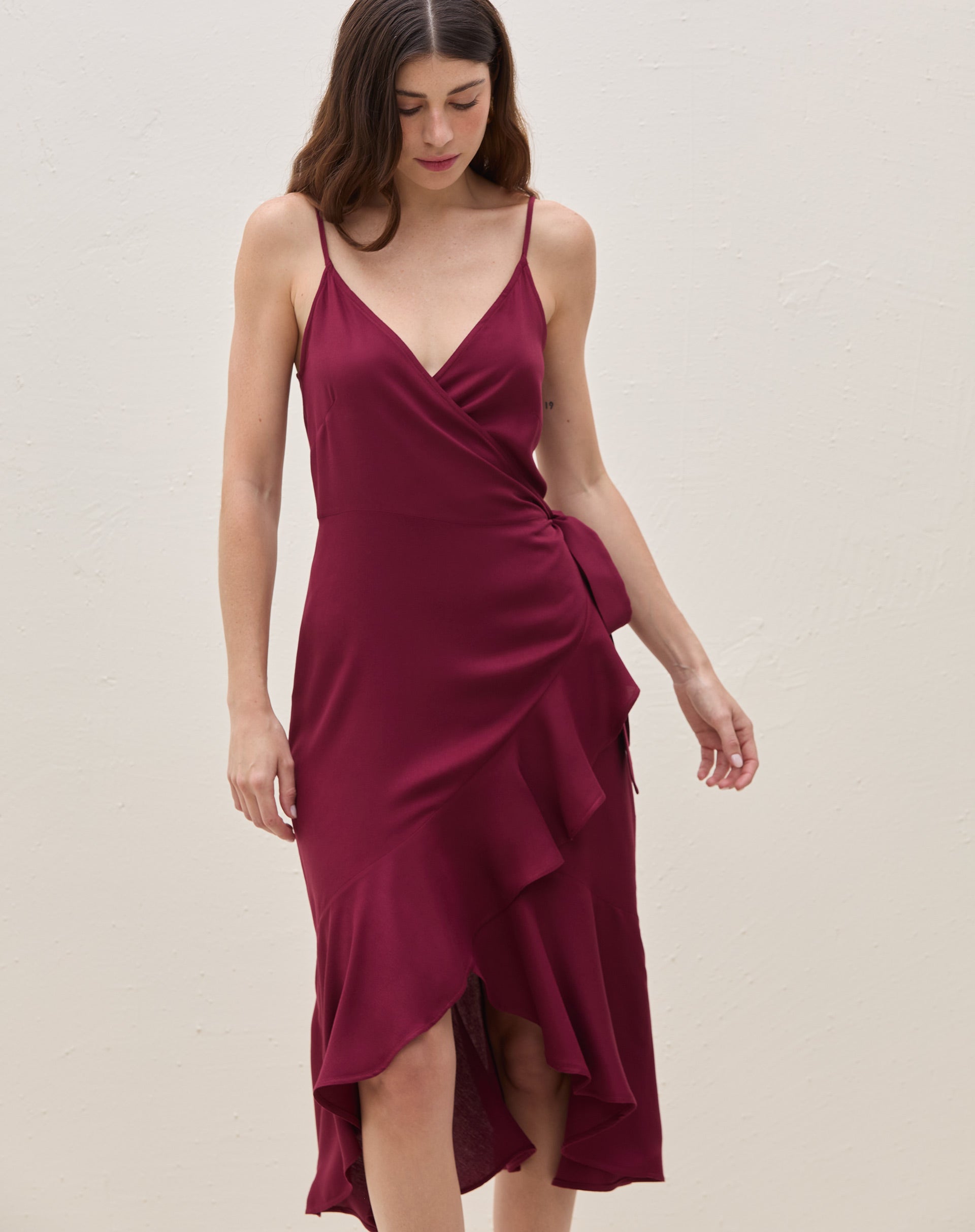 Vestido midi transpassado vinho mostrando amarração lateral na cintura e babado lateral — vista 3/4 lateral destacando o caimento.