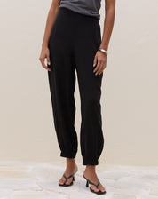 Detalhe da barra elástica da calça jogger preta - punho franzido com elástico e acabamento costurado