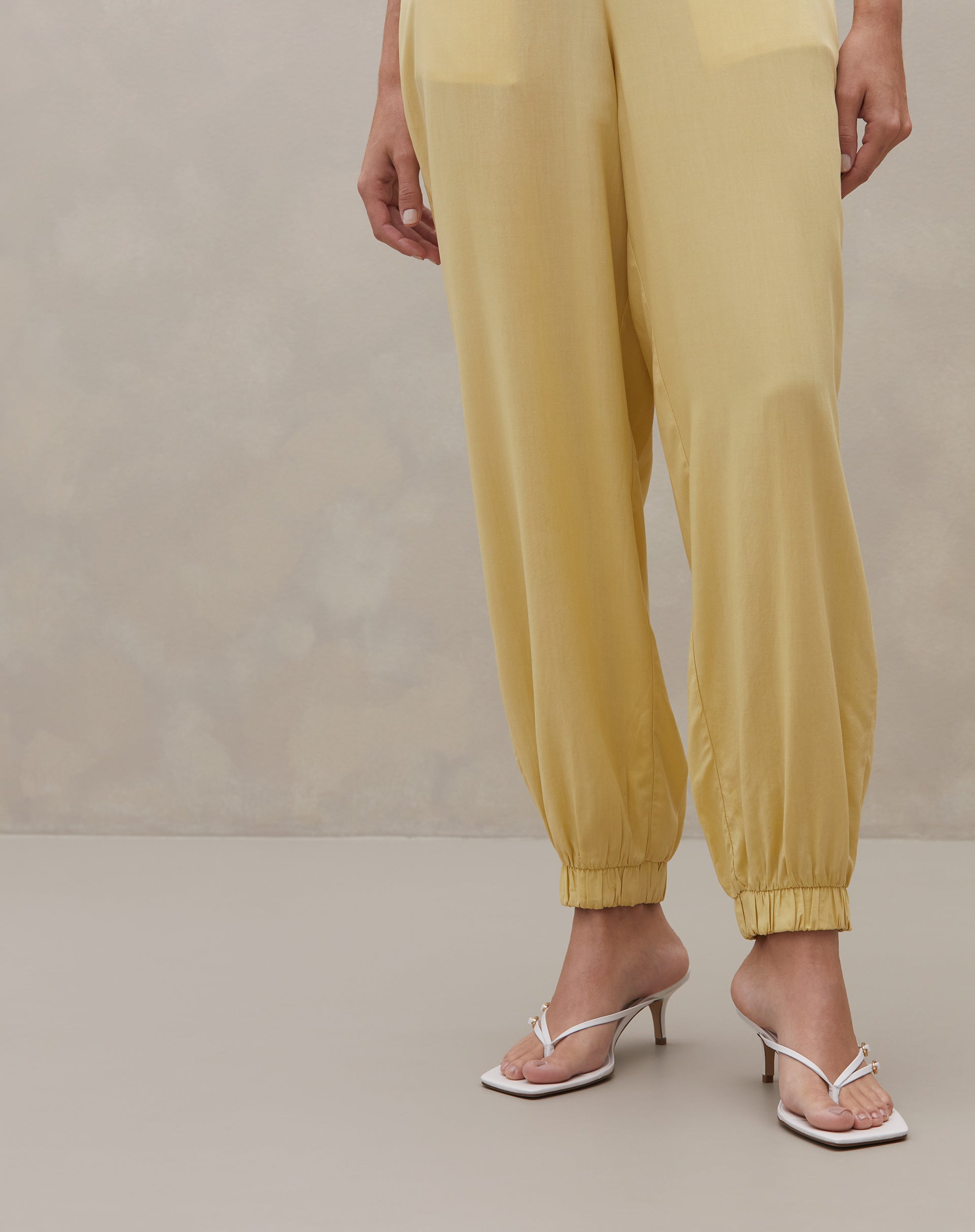 Detalhe das pernas da Calça Jogger Aladim mostrando punhos elásticos e caimento fluido em tom manteiga