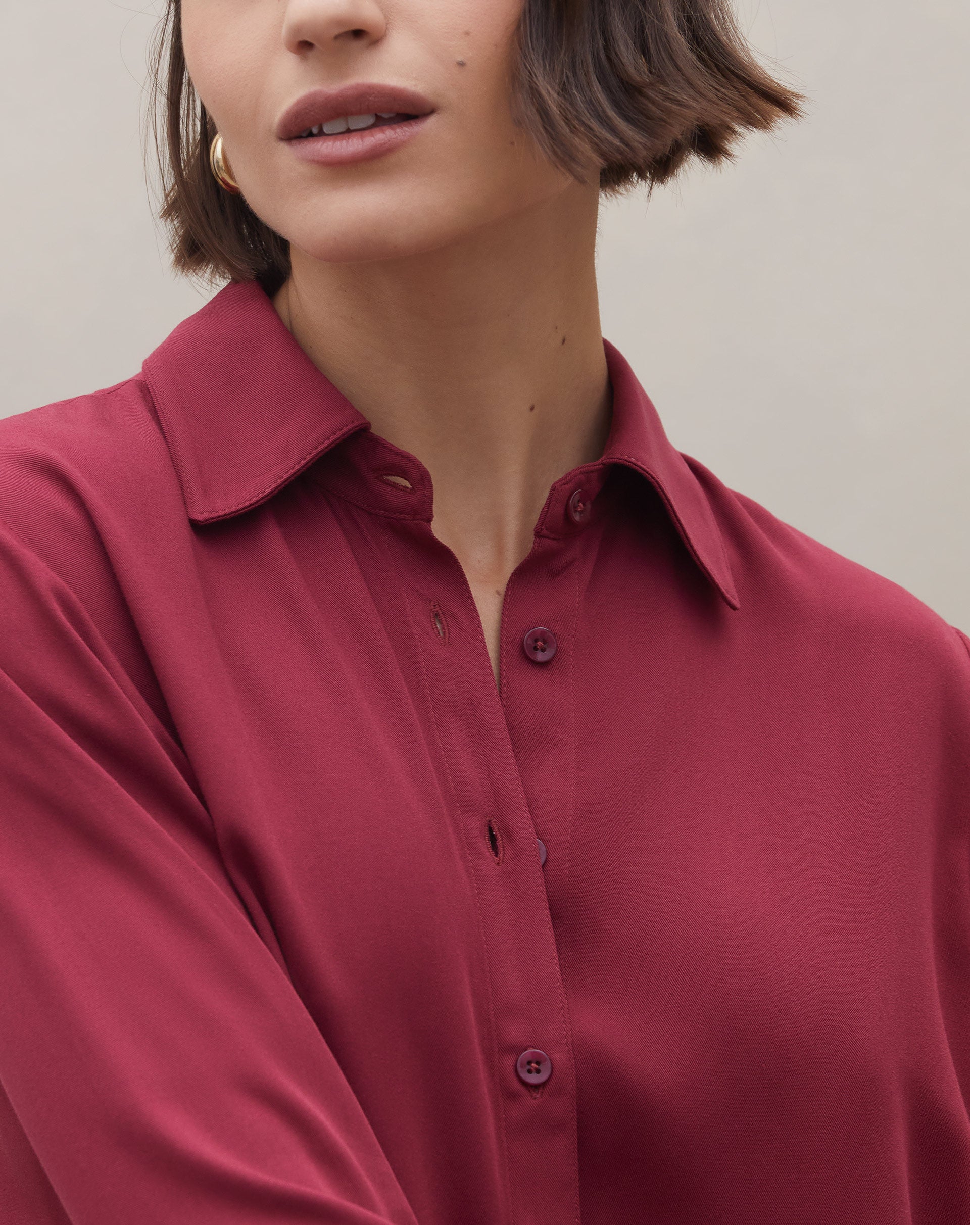 Close no decote e botões da camisa viscose vinho, destacando gola clássica e acabamento liso